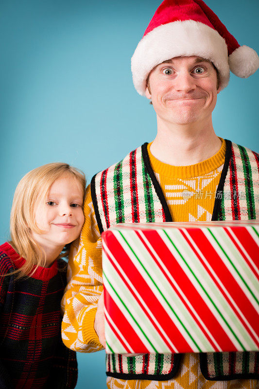 戴着圣诞帽和丑陋毛衣的男人和小女孩