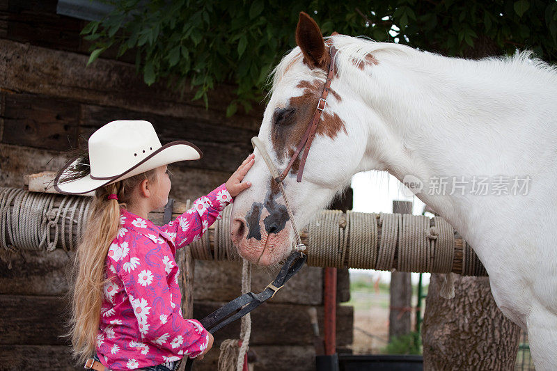 戴着牛仔帽的小女牛仔抚摸着她的马