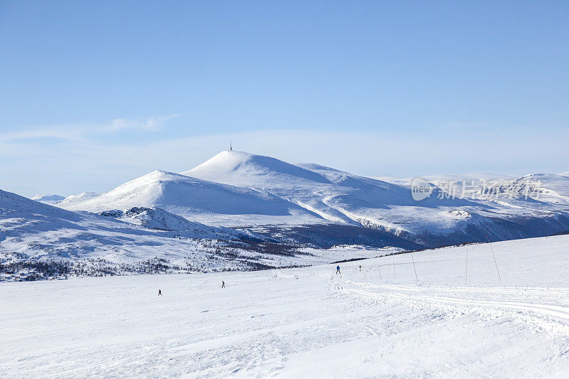 人们在天空湛蓝的挪威山上滑雪。