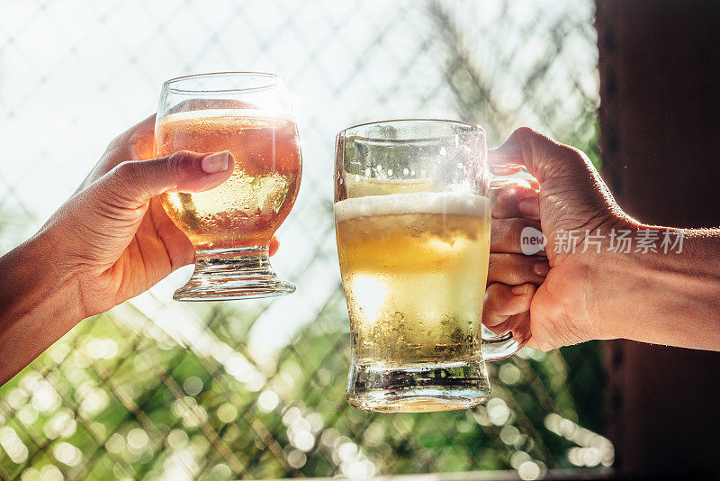 两只手在夏日的阳光下碰杯