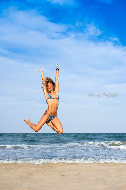 年轻女子跳跃与海洋背景