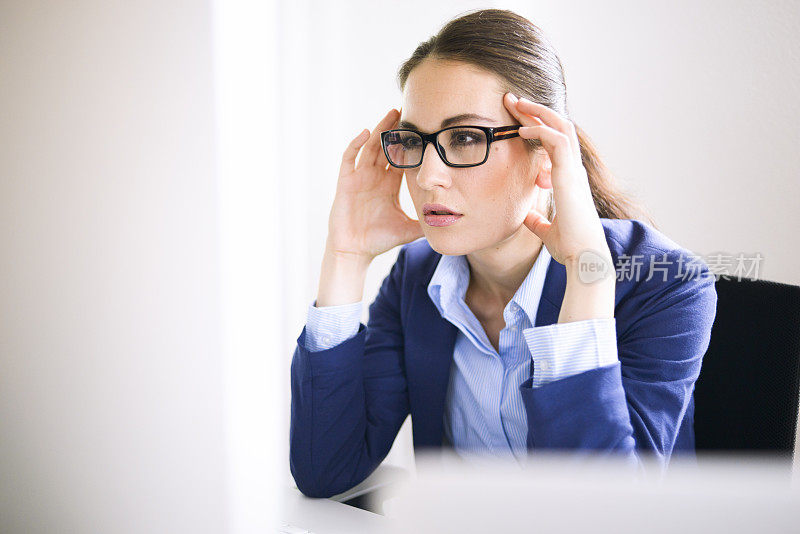 戴眼镜专注于电脑显示器的女商人