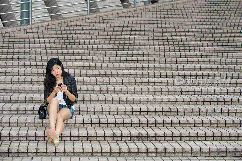 坐在楼梯上打电话的亚洲女人