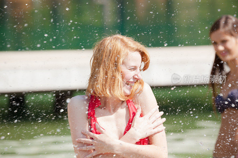 漂亮的红发女孩在夏天游泳溅起水花