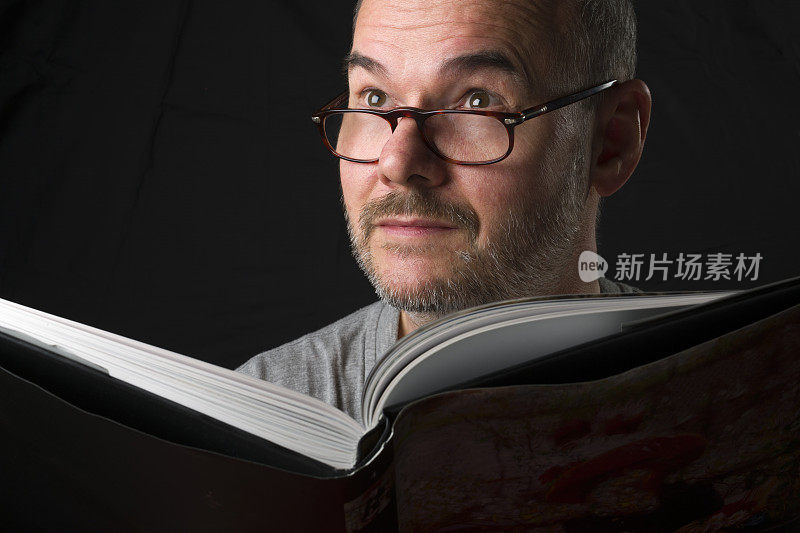 一个胡子戴眼镜的男人在阅读宗教书籍时获得灵感