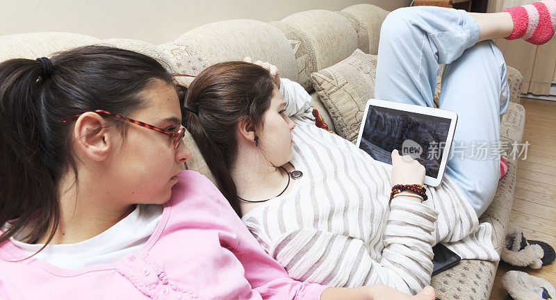 两个少女姐妹在客厅玩平板电脑