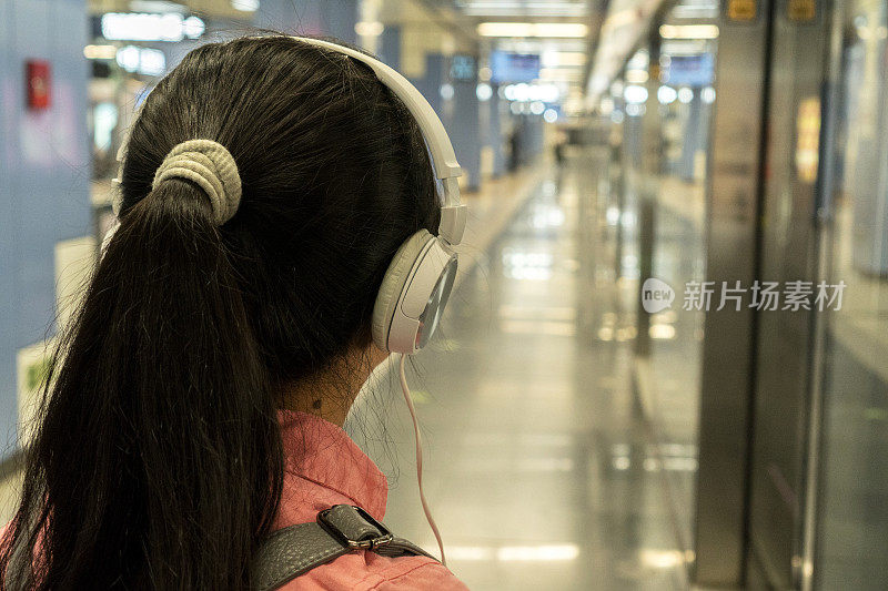 女孩在地铁站听音乐