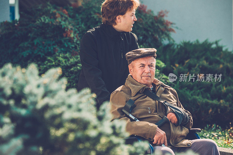 坐在轮椅上的老人和他的孙子在公园，欧洲