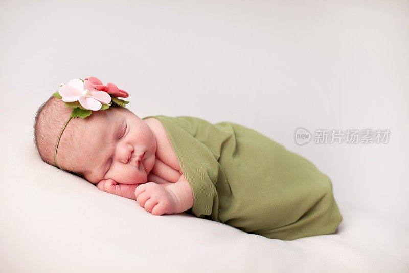 新生儿包裹在绿色毯子里的彩色图像