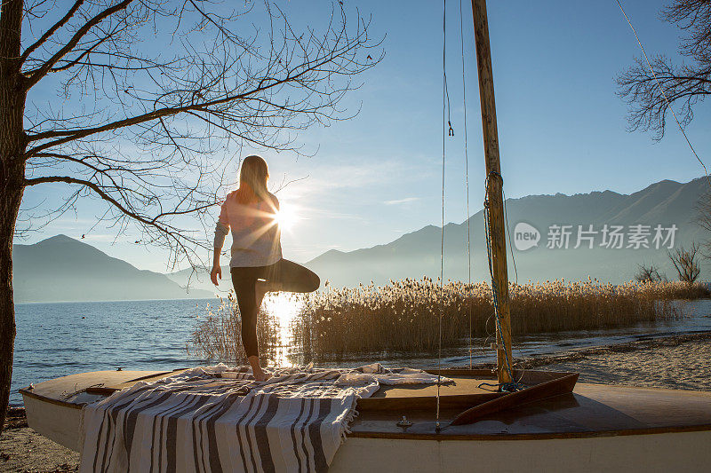 日落时分，年轻女子在湖边做瑜伽