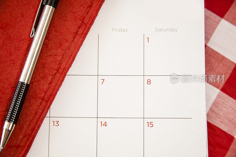 空白日历月，红色日记本和钢笔。