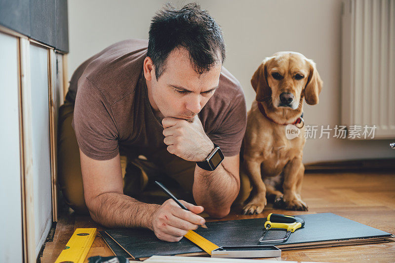 男人和他的狗在家里做装修工作