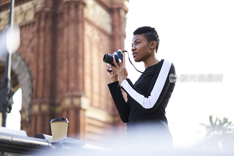 美丽的非洲裔美国女摄影师拍摄的城市风景散步户外，有吸引力的年轻创意潮女孩短发去观光，使照片的著名地方