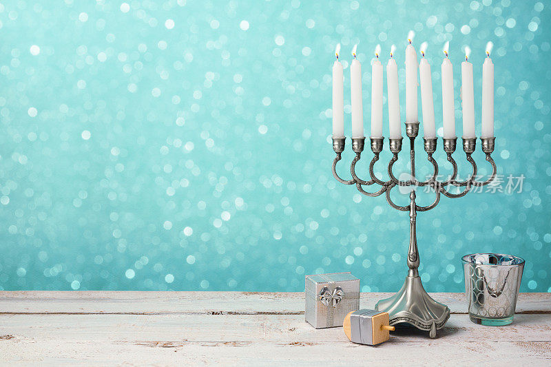 犹太光明节的庆祝活动，木制的桌子上放着烛台、陀螺和礼物