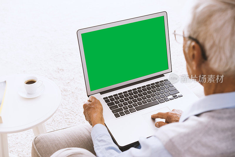 一个老人在用绿屏笔记本电脑