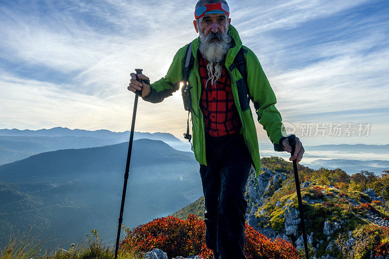 快乐的老年人远足在秋天的黎明在朱利安阿尔卑斯山，斯洛文尼亚，欧洲