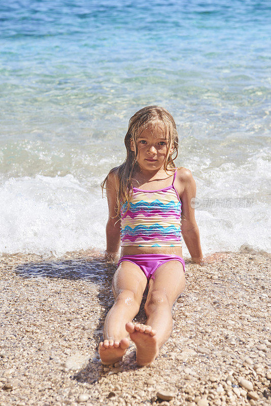 金发小女孩在海滩上享受海浪