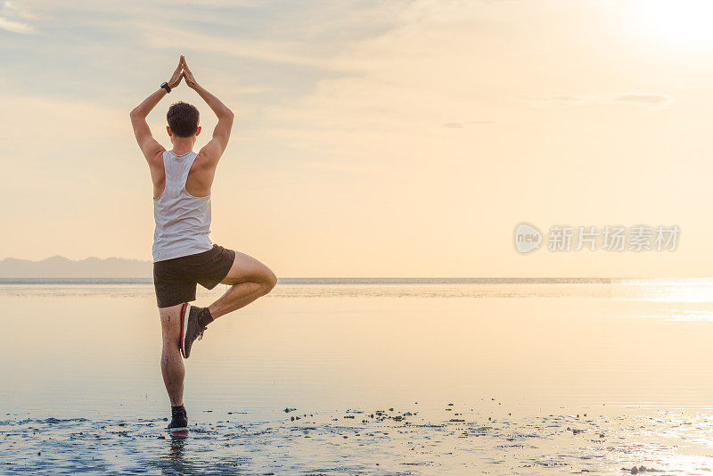 年轻的亚洲男子在日落海滩做瑜伽运动