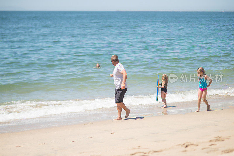 一个阳光明媚的下午，爱运动的爸爸和他的女儿们在海滩上玩耍