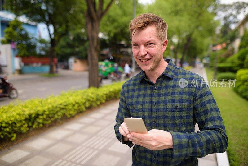 越南胡志明市的街道上，年轻帅气的游客正在使用手机