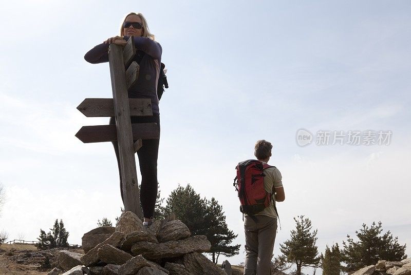 意大利皮埃蒙特，一名徒步旅行者站在路标旁，同伴望向远处