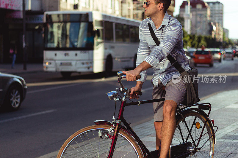 时髦的男人在城市的街道上骑自行车