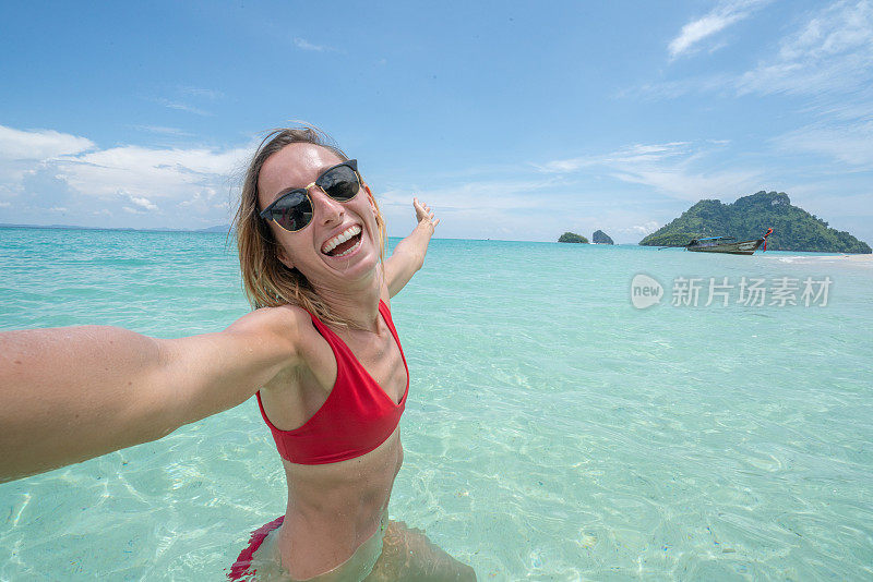 一个年轻的女人在泰国岛屿的原始清澈的水田园般的海滩上自拍。人们旅行豪华度假乐趣和酷的态度概念