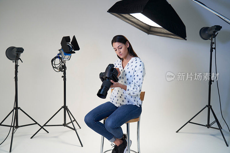 女性摄影师在摄影工作室拍摄与相机和照明设备