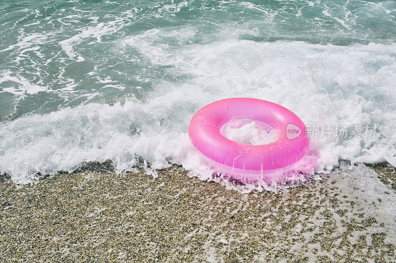 粉红色的橡胶圈在海浪上，阳光灿烂的夏日。