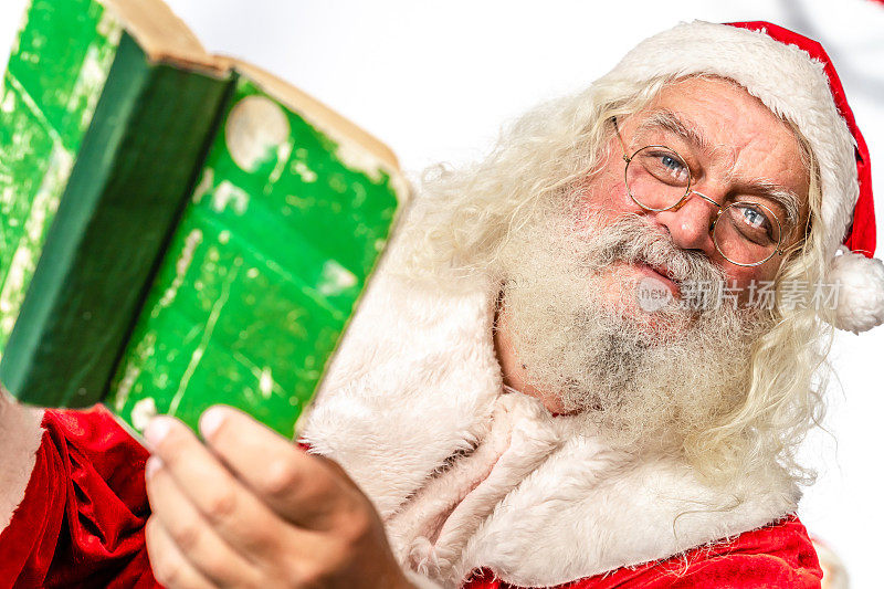 圣诞老人看着镜头，拿着绿皮书