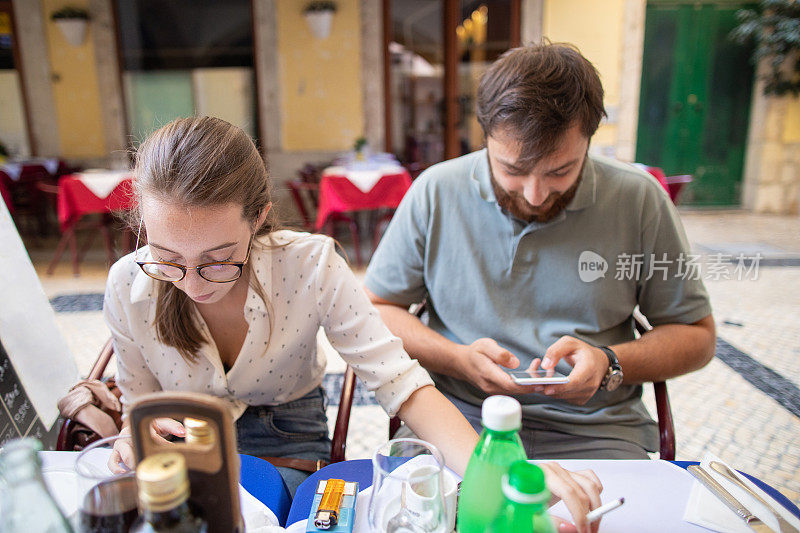 一对年轻的游客夫妇在路边咖啡馆吃午餐