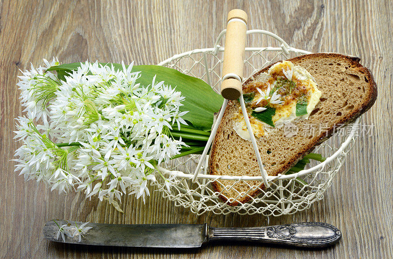 的早餐。一束可食用的ramson野蒜花，放在篮子里，配上面包和黄油。