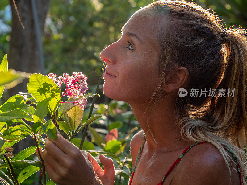 年轻女子在热带花园里闻着花香