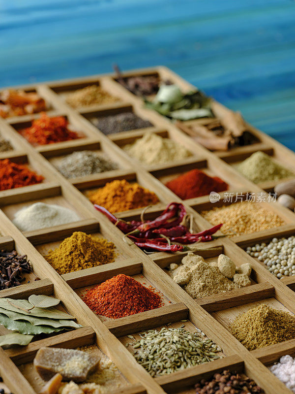 各种彩色的，有机的，干燥的，充满活力的印度食物香料在一个古老的绿松石色的背景木托盘，与大气的照明。