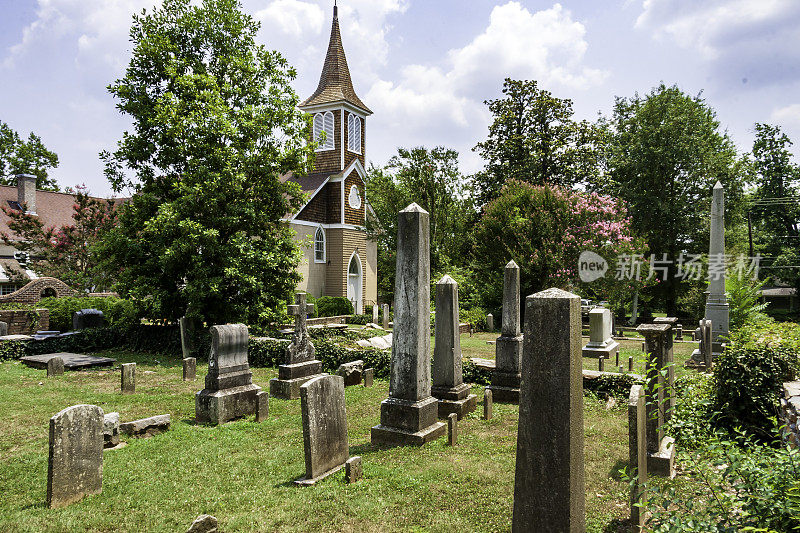 典型的南方乡村教堂，有各种各样的树，草，古老的，破旧的墓碑，在一个精心照料的墓地