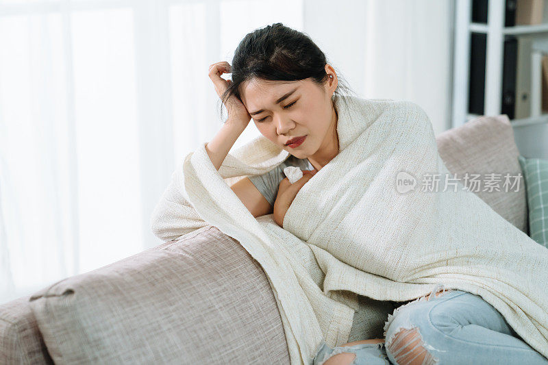 生病的亚洲妇女盖着温暖的毯子
