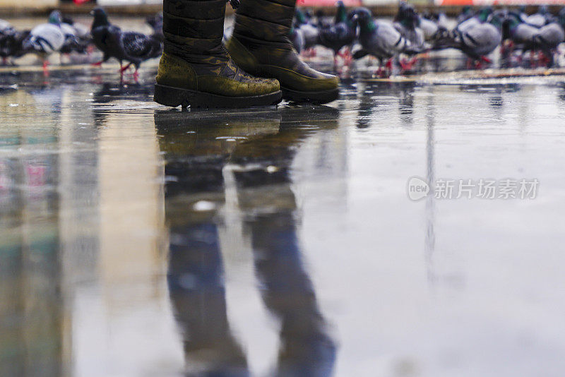 脚在胶靴雨水坑城市