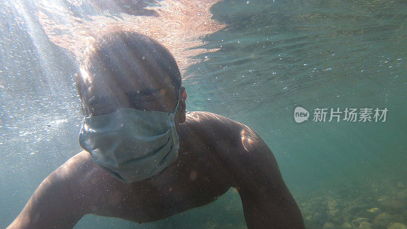 年轻的成年男子戴着防护面具在夏天的水中度假