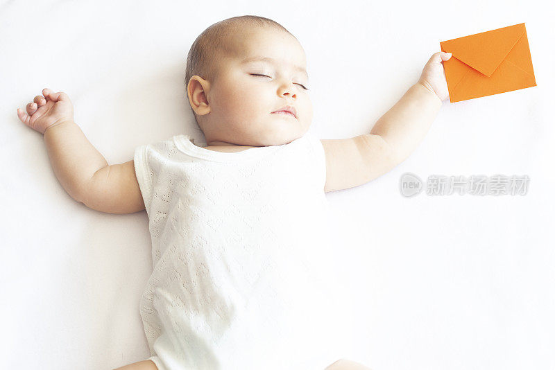 美丽的睡着的婴儿拿着橙色的信封