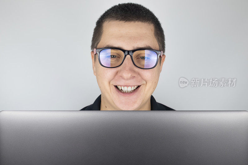 这个人看了看笔记本电脑，笑了，对他看到的东西感到惊讶。对你在互联网上看到的东西的情绪和反应的表达。震撼内容的概念。