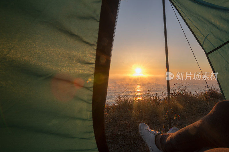 清晨，妇女们在帐篷里看着海面上的日出