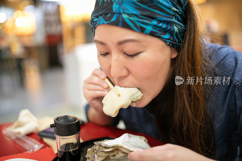 一个女人正在吃一个巨大的新鲜牡蛎