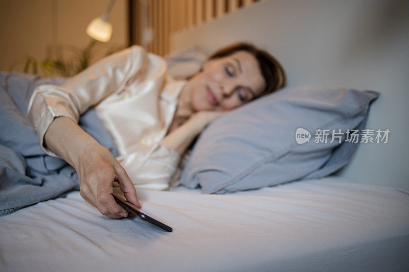 成熟的女人在床上，一觉醒来就看智能手机