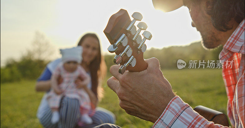 日落时分，一家人带着孩子和吉他在大自然中远足。春天的居家旅游。