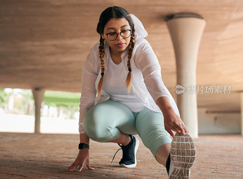 这张照片拍摄的是一位运动的年轻女子在户外锻炼时伸展双腿