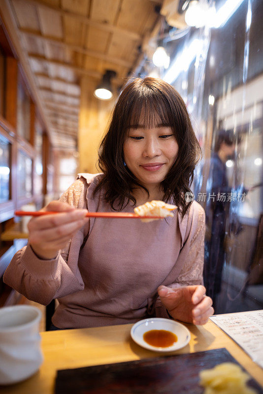 在户外餐厅吃寿司的女人