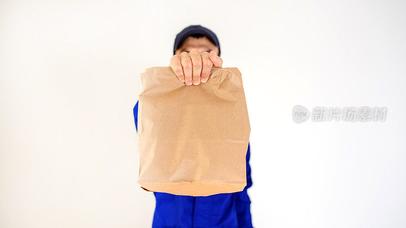 近距离拍摄一个快递员的手，拿着一个生态纸袋。