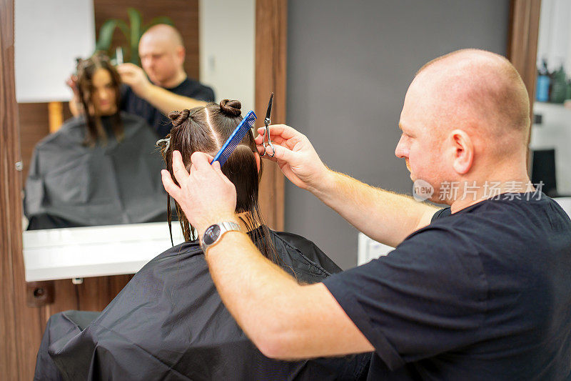 男造型师在专业美容院为女客户理发。