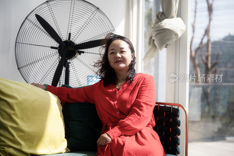 一个穿红衣服的女人拿着吹风机坐在沙发上