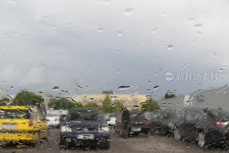 雨滴落在车窗玻璃上，有一辆车和一个人的轮廓